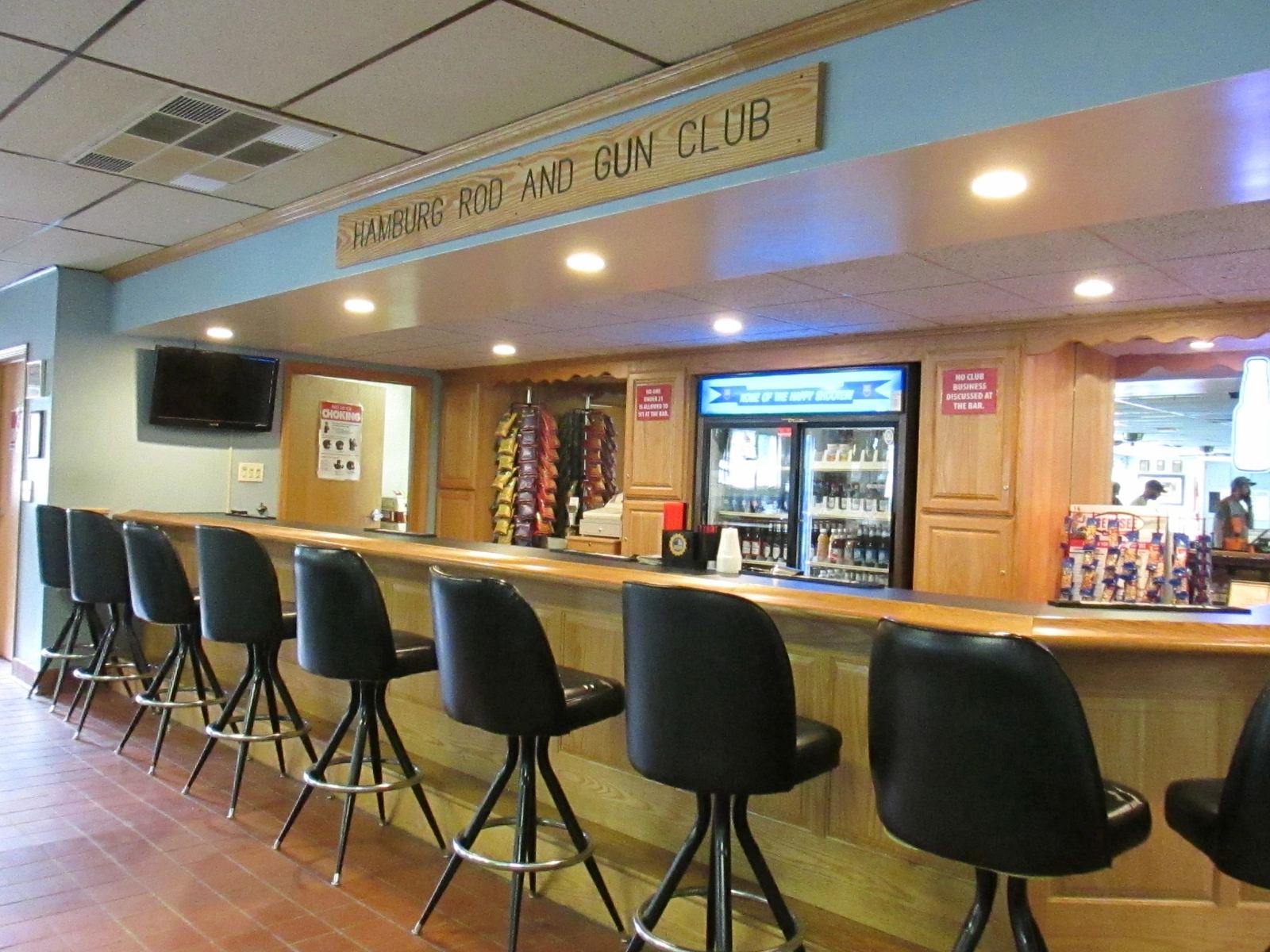 The club bar with stools and a Hamburg Rod and Gun Club sign