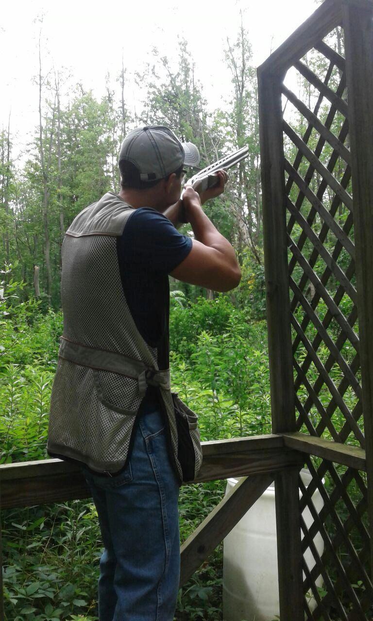 Shooter taking aim from a sporting clays station in the woods